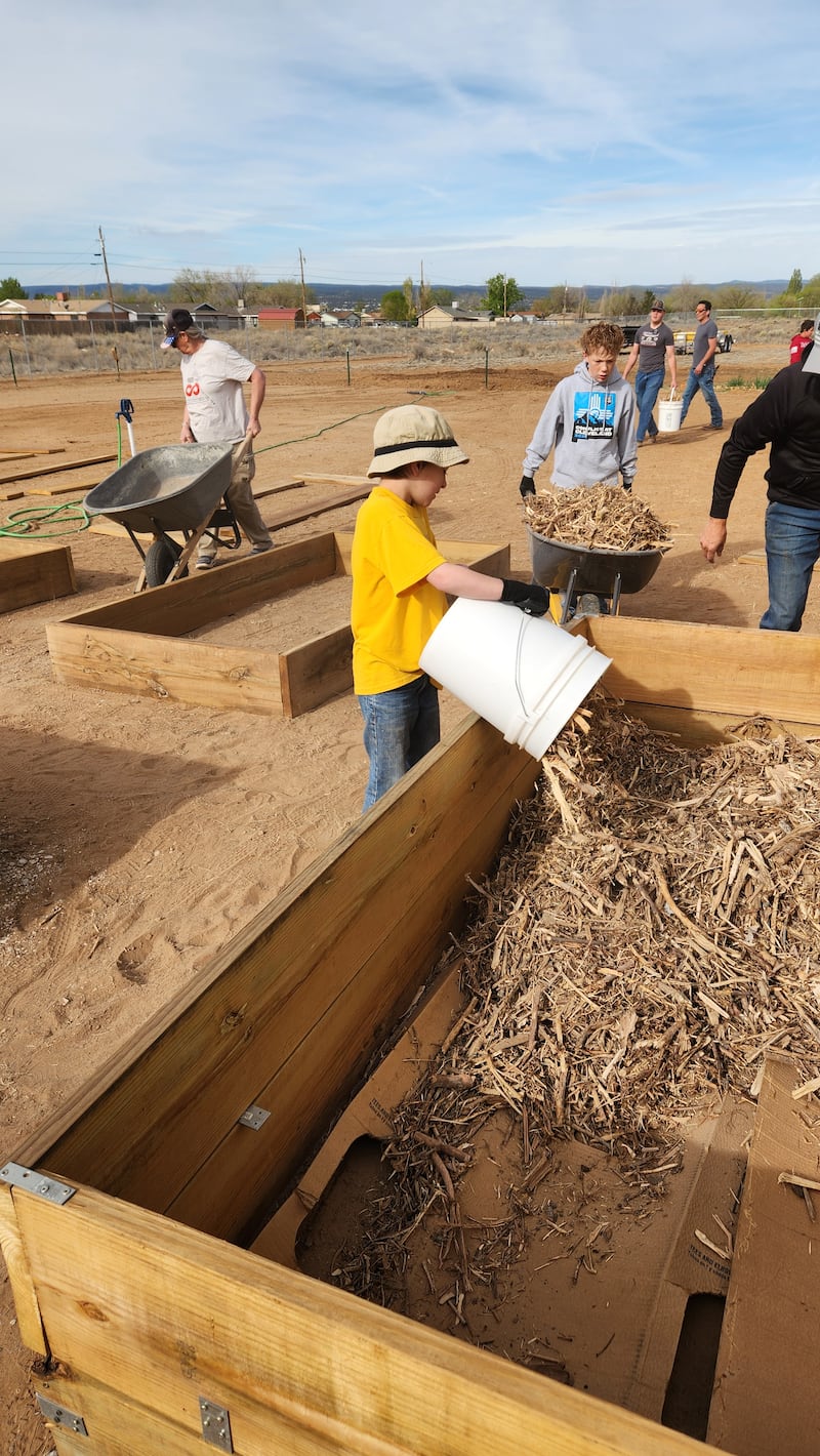 Jóvenes y adultos preparan nuevas cajas de huerto en la Despensa Comunitaria y Huerto de Esperanza en Grants, Nuevo México, el 11 de abril de 2026.