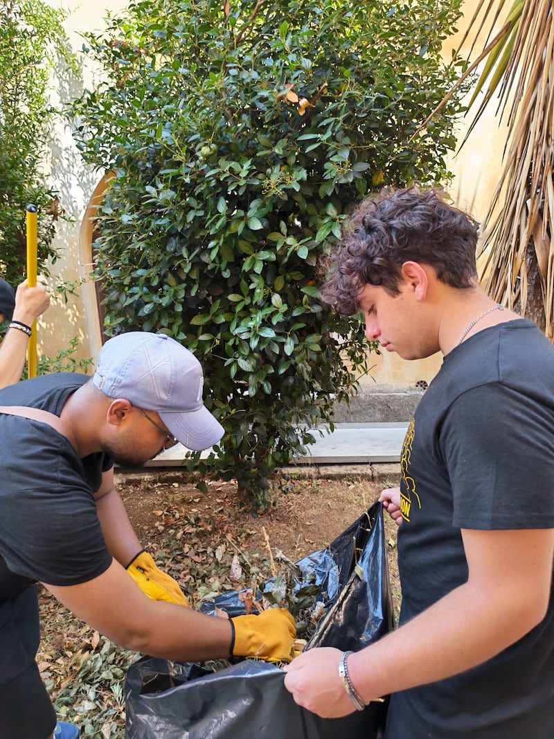 Voluntarios de la Estaca Palermo Italia recogen hojas y escombros del jardín mientras limpian los terrenos de Casa Scalabrini 634 en Roma, Italia.
