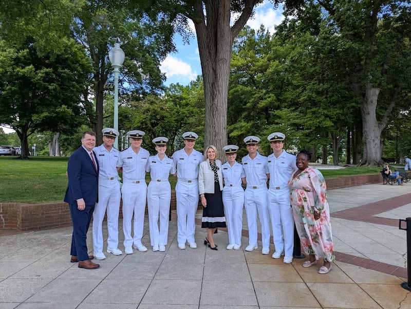 La presidenta Camille N. Johnson, el élder Michael P. Brady y la hermana Eme Martin se toman una foto con siete Santos de los Últimos Días que actualmente son guardiamarinas en la Academia Naval de los Estados Unidos en Annapolis, Maryland, el viernes 15 de mayo de 2026.