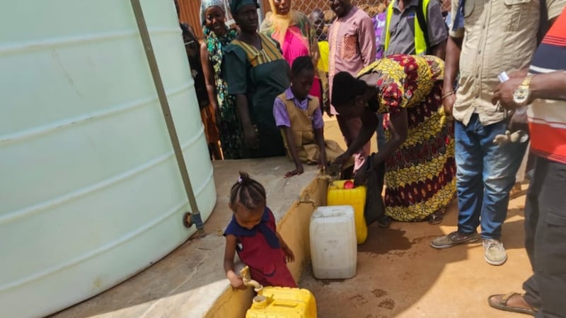 Residentes de la comunidad llenan recipientes con agua limpia después de una ceremonia de entrega en el oeste de Freetown, Sierra Leona, el 3 de abril de 2026.