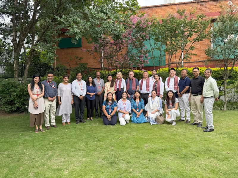 La presidenta y el hermano Johnson, el élder y la hermana Tai, posan para una foto con varias personas en Katmandú, Nepal.