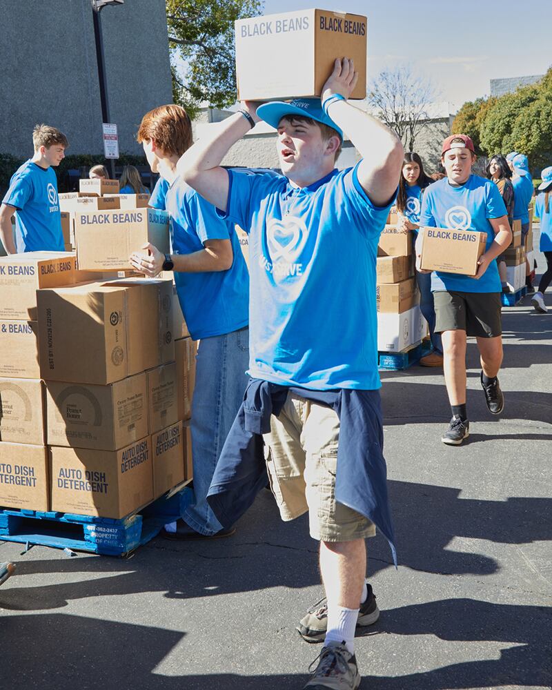 Joseph Gleason, un joven voluntario de JustServe, ayuda a mover cajas de una donación de alimentos de America250 de La Iglesia de Jesucristo de los Santos de los Últimos Días a palés para su entrega a casi una docena de organizaciones benéficas diferentes en el área de Irvine, California, el sábado 21 de febrero de 2026.