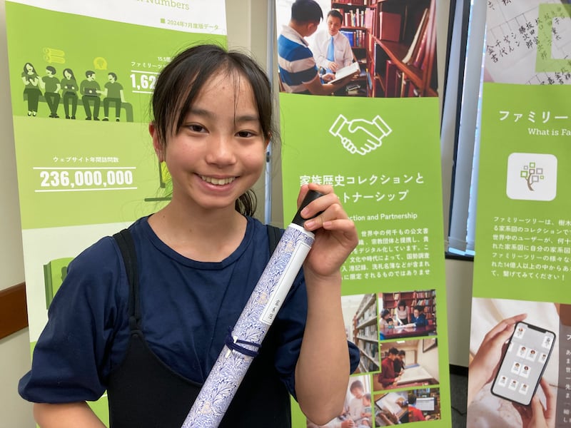 Una niña muestra un pergamino genealógico que hizo durante una feria de historia familiar en Kagoshima, Japón, el 23 de febrero de 2026.