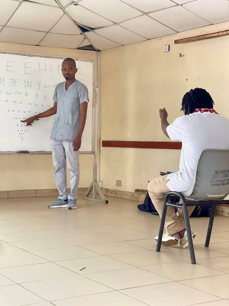Adolphus Togbah, a la izquierda, realiza un examen de la vista en una clínica gratuita establecida en una escuela en Liberia.
