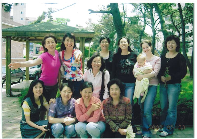 Traci Law — compositora del nuevo himno "Pequeño Bebé en un Pesebre", a la derecha — sonríe con hermanas de su barrio en Ulsan, Corea, en 2007.