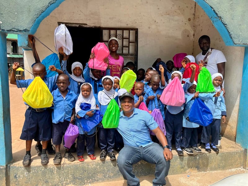 Konrad Barjuah, en el centro, entrega kits escolares a una escuela en Liberia.