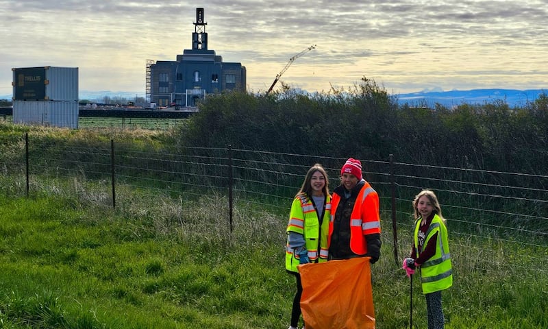 Jóvenes mujeres recogen basura a lo largo de la autopista cerca de Rexburg, Idaho, como parte del Día Global del Servicio Juvenil el sábado 25 de abril de 2026. El Templo de Teton River Idaho está en construcción al fondo.