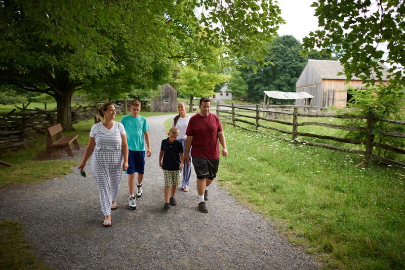 Una familia camina cerca de la granja de la familia de Joseph Smith en el sitio histórico de la Arboleda Sagrada en Palmyra, Nueva York, en agosto de 2018.