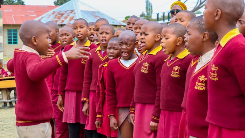 Un coro escolar con uniformes rojos idénticos canta para la Presidenta General de la Primaria, Susan H. Porter, mientras ella visita la Escuela Primaria St. Louis cerca de Maseru, Lesoto, el viernes 5 de septiembre de 2025.