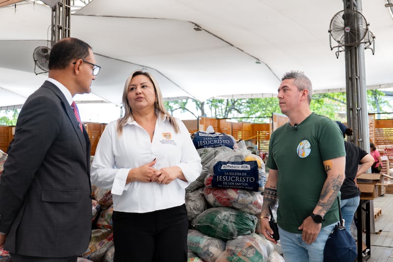 Élder Harold Truque, una Setenta Autoridad General del área de Cali, Colombia, a la izquierda; habla con Natalia Lasso, asesora de la alcaldía de Cali, al centro; en un centro de acopio principal para distribuir 1 000 kits de alimentos a varias áreas afectadas por un terremoto en Cali, Colombia, en agosto de 2026.