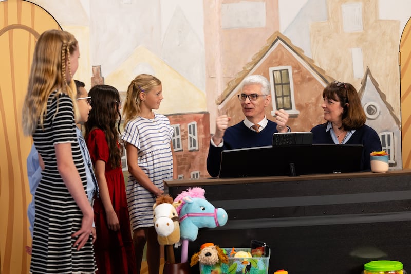 El élder Gérald Caussé del Cuórum de los Doce Apóstoles y su esposa, la hermana Valérie Caussé, se preparan para cantar con un grupo de niños durante la transmisión Amigo a Amigo de septiembre de 2026.