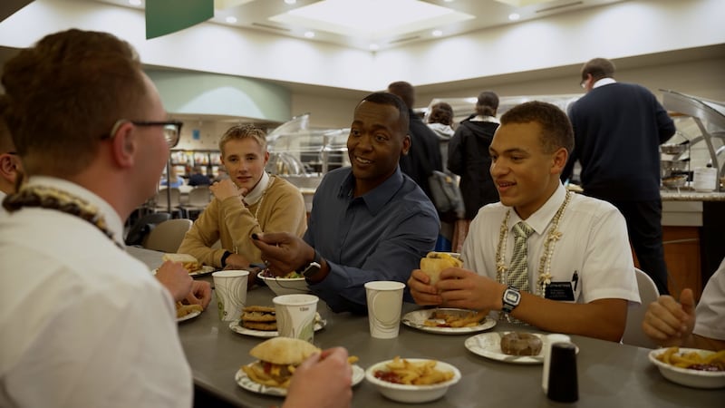 Los misioneros conversan con el presentador del video Danor Gerald mientras comen en la cafetería en el Centro de Capacitación Misional de Provo.