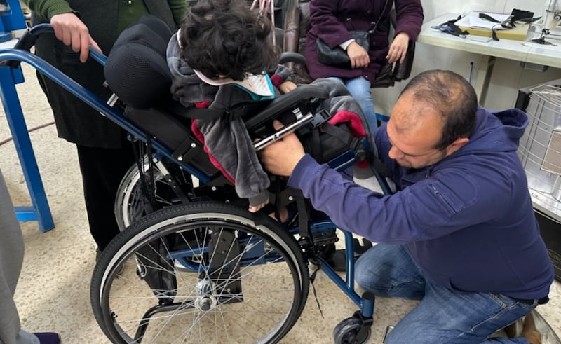 Un niño es equipado con su silla de ruedas especializada por un especialista.