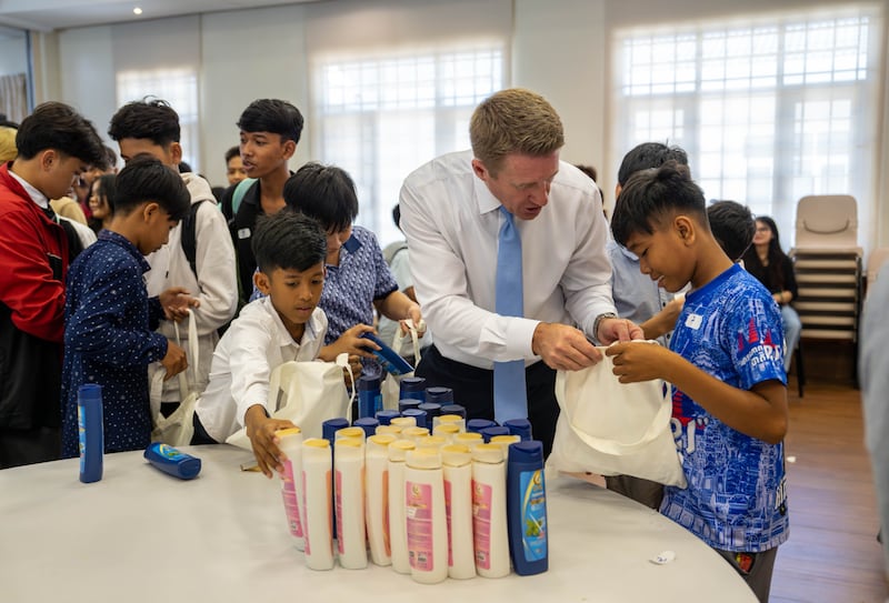 El presidente general de los Hombres Jóvenes, Timothy L. Farnes, ayuda a un joven durante un proyecto de servicio para ensamblar más de 200 bolsas de cuidado para un orfanato en Phnom Penh, Camboya, en mayo de 2026.