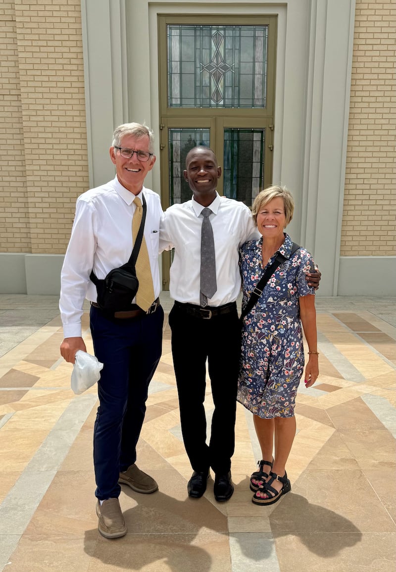 Kilford Shereni aparece en una fotografía con Bruce y Elizabeth Anderson frente al Templo de Harare, Zimbabue.