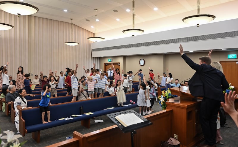 Durante su ministerio en Singapur, el presidente general de los Hombres Jóvenes, Timothy L. Farnes, invitó a los niños a ponerse de pie, levantar las manos y comprometerse a leer las Escrituras diariamente.