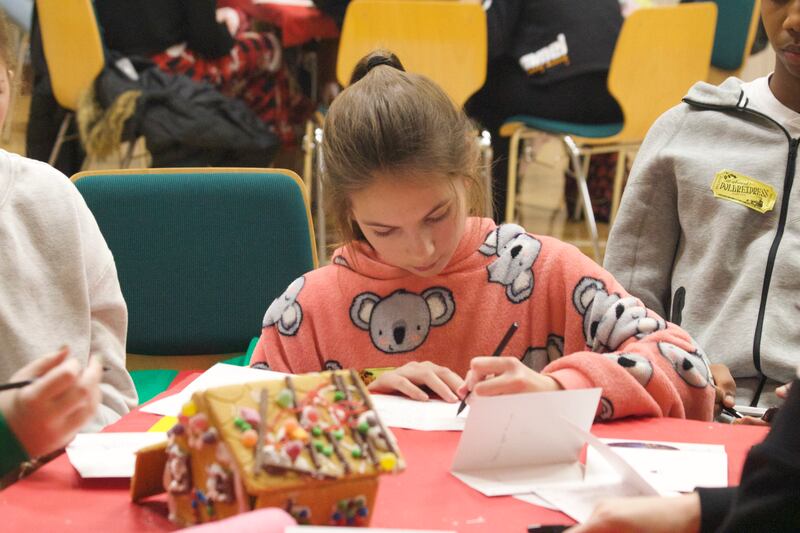 Jóvenes en la Estaca Northampton Inglaterra escriben tarjetas en una mesa para enviar a otros como parte de una actividad de servicio en diciembre de 2024.