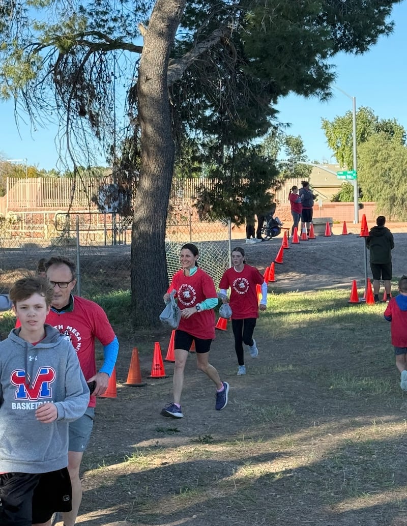 Los participantes corren hacia la meta con bolsas de comestibles llenas de alimentos donados durante la segunda carrera anual de comestibles del Noreste de Mesa en Mesa, Arizona, el 21 de febrero de 2026.