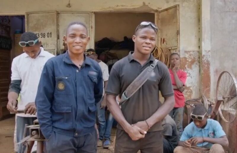 Alexis Ahouayito, a la derecha, se encuentra junto a su jefe y mentor, el obispo Darmande Legbanon, en Benín, África Occidental. El obispo Legbanon animó a Ahouayito a asistir al programa Éxito en la Escuela, mientras era aprendiz en el taller de soldadura del obispo.