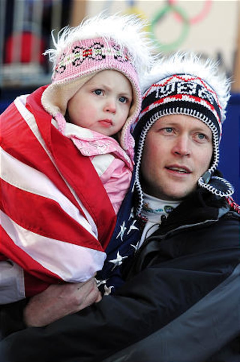 Janson Pace sostiene a su hija, Jacee, mientras observan a su esposa y madre Noelle Pikus Pace de los Estados Unidos competir en la tercera serie del skeleton femenino el viernes en los Juegos Olímpicos de Invierno de Vancouver 2010 en el Centro de Deslizamiento de Whistler.