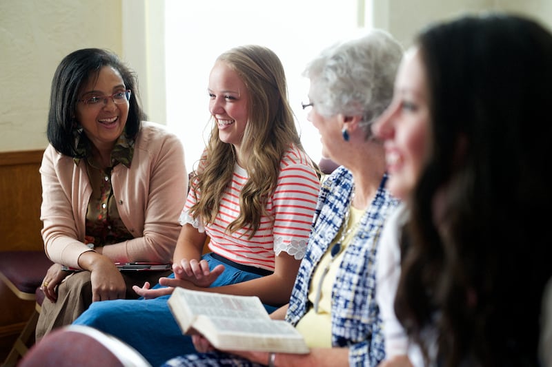 Una joven interactúa con mujeres mayores en un entorno de la Iglesia.