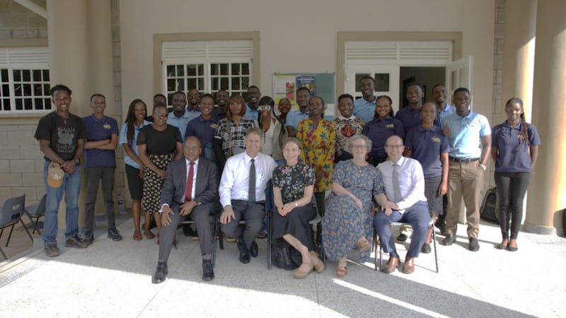 El élder Frederick Kamya, el élder Carl B. Cook, la hermana Lynette Cook, la hermana Isabelle Giraud-Carrier y el élder Christophe Giraud-Carrier se toman una foto con los líderes de los JAS en la Estaca Kampala Uganda Norte el 17 de marzo de 2026.