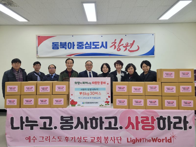 Los líderes del área de Changwon, la Universidad de Masan y varias organizaciones benéficas posan detrás de cajas de kimchi preparado en Changwon, Corea del Sur, el 12 de diciembre de 2025.