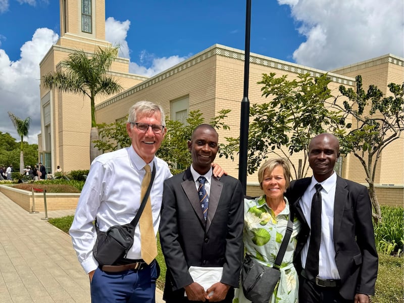 Kilford Shereni y Reginald Magocha posan para una foto con Bruce y Elizabeth Anderson frente al Templo de Harare, Zimbabue.