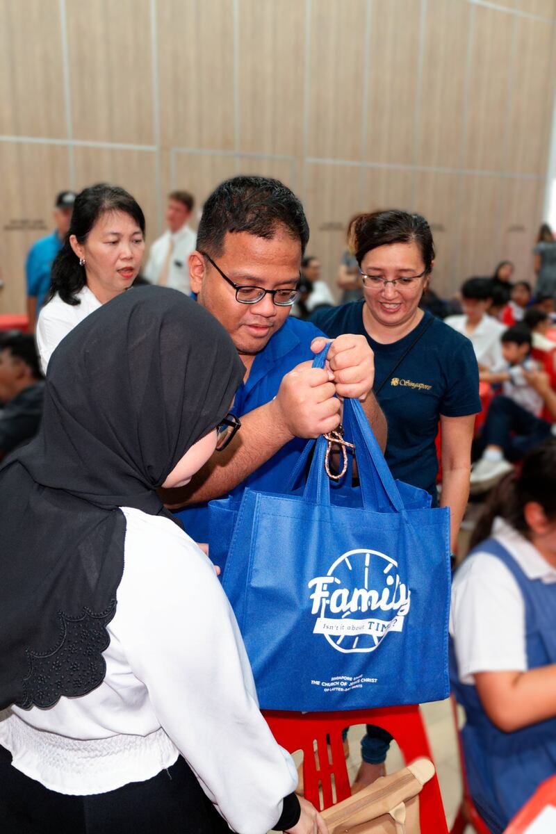 Miembros de La Iglesia de Jesucristo de los Santos de los Últimos Días y voluntarios de la Fundación Rahmatan Lil Alamin entregan bolsas de raciones secas donadas a un receptor en el proyecto de servicio de Premios de Estudio en el Centro Comunitario de West Coast en Singapur, el 6 de diciembre de 2025.
