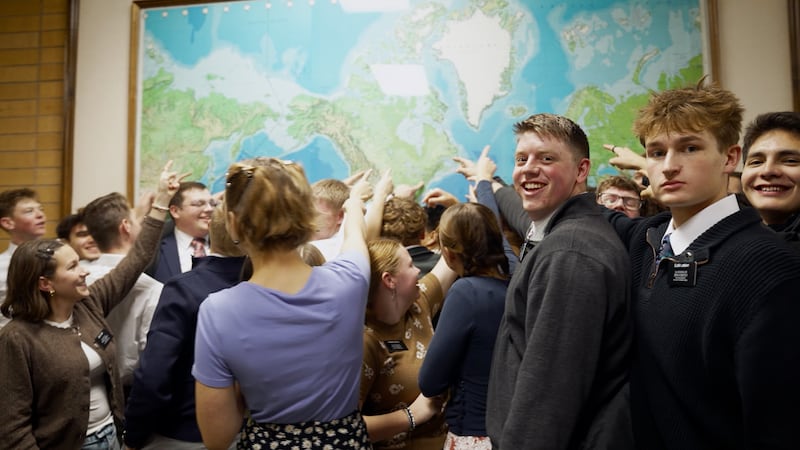 Los misioneros señalan su misión asignada en un mapa mundial durante la grabación de un nuevo video en el Centro de Capacitación Misional de Provo.