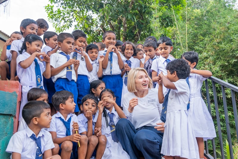 La Presidenta General de la Sociedad de Socorro, Camille N. Johnson, conversa con niños escolares con uniformes en Sri Lanka.