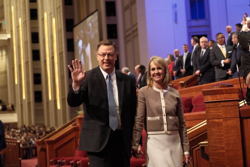El élder Clark G. Gilbert, del Cuórum de los Doce Apóstoles, saluda mientras él y su esposa, la hermana Christine Gilbert, salen al final de la sesión del sábado por la tarde de la Conferencia General número 196 de La Iglesia de Jesucristo de los Santos de los Últimos Días, celebrada en el Centro de Conferencias en Salt Lake City el sábado 4 de abril de 2026.