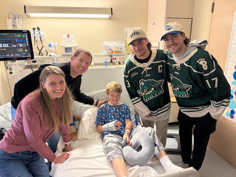 Nate Cooper, de 9 años, en el centro, hijo de Allie y Lee Cooper, a la izquierda, recibe la visita de los jugadores de hockey de los Idaho Steelheads Nick Canade y Ty Pelton-Byce del equipo de hockey Idaho Steelheads en el Hospital Infantil St. Luke's en Boise, Idaho, el 10 de marzo de 2026.
