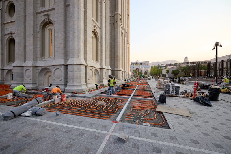 Las cuadrillas instalan pavimento de piedra sobre tuberías de deshielo de nieve fuera del Templo de Salt Lake en Salt Lake City el martes, 23 de junio de 2026.