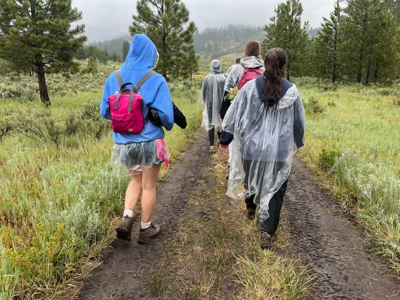 Los jóvenes de la Estaca Spokane Valley Washington caminan bajo la lluvia durante Trek en Bend, Idaho el 26 de junio de 2026.