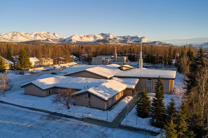 El Centro de Estaca de Anchorage, Alaska se muestra en primer plano, con el Templo de Anchorage, Alaska detrás.