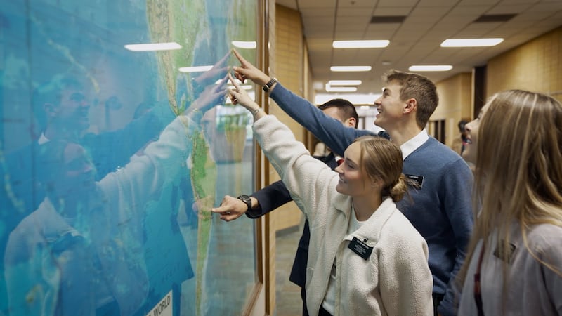 Los misioneros señalan su misión asignada en un mapa mundial durante la filmación de un nuevo video en el Centro de Capacitación Misional de Provo.