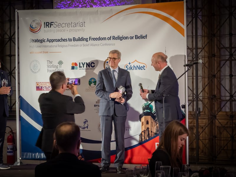 El profesor Brett Scharffs del Centro Internacional para Derecho y Estudios Religiosos de la Universidad Brigham Young recibe un premio por su compromiso de larga data con la defensa de la libertad religiosa del embajador Robert Řehák, Presidente de la Alianza del Artículo 18, durante una ceremonia de premiación en el histórico Museo Nacional en Praga, República Checa, el 12 de noviembre de 2025.