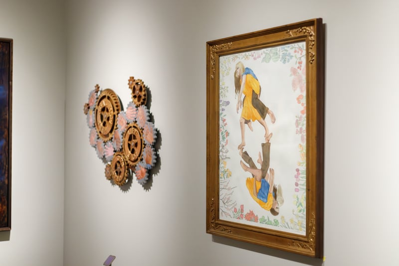 La pintura de Claire Forste "Te levanto; Me levantas", a la derecha, muestra a dos mujeres que se turnan para cargarse mutuamente. La pintura es parte de la exposición del 13.º Concurso Internacional de Arte de la Iglesia en el Museo de Historia de la Iglesia hasta enero de 2026.