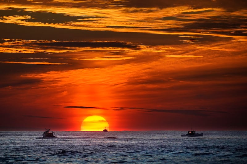 El sol sale sobre botes de pesca en el océano Atlántico, 8 de septiembre de 2022, en las costas de Kennebunkport, Maine.