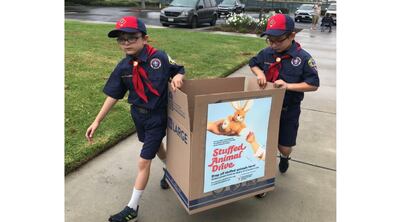 Dos miembros del San Diego-Imperial Council de Boy Scouts of America llevan una caja de animales de peluche para la campaña anual de la Casa de Ronald McDonald el 23 de octubre de 2021.