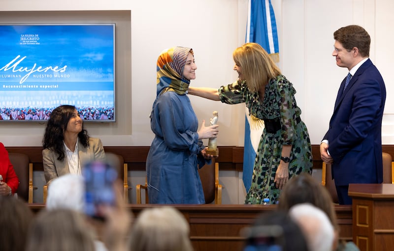 El élder Alan R. Walker y la hermana Inés Walker sonríen a Sümeyra Nur Korkut durante la ceremonia "Mujeres que iluminan" en Buenos Aires, Argentina, el 19 de marzo de 2026.