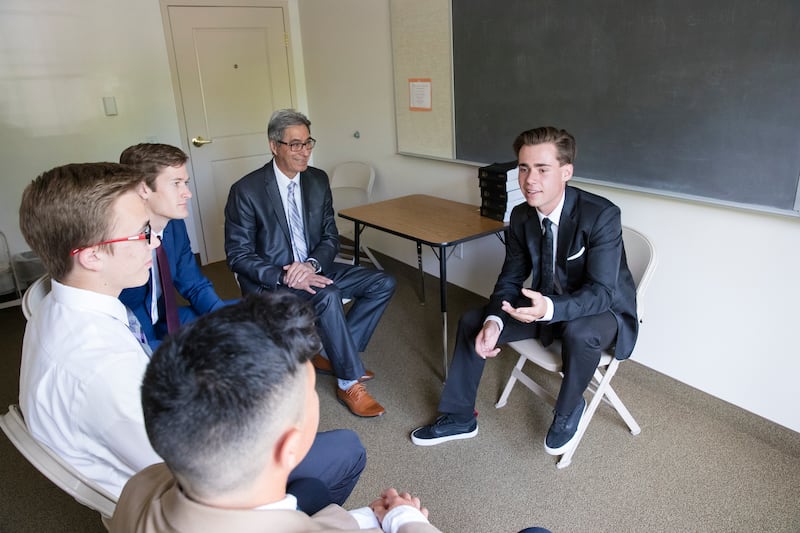 Los hombres jóvenes conversan durante una reunión de quórum en el Día de Reposo.