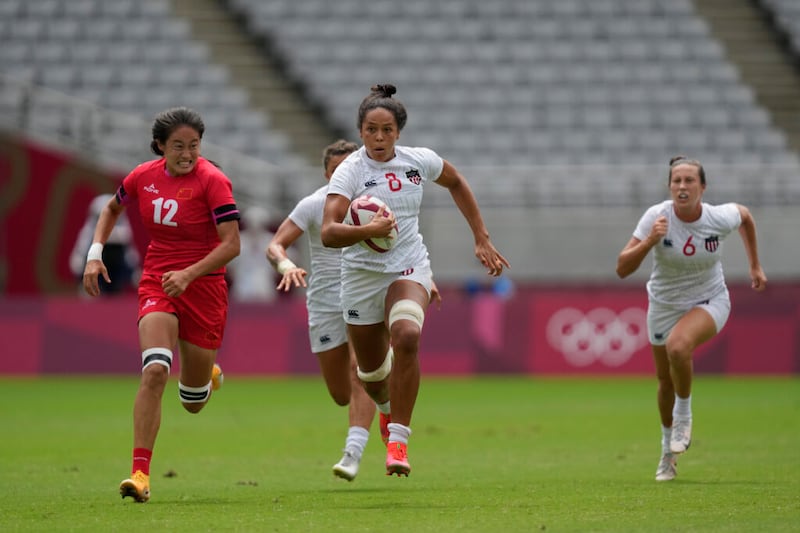 Jordan Matyas, de Estados Unidos, en el centro, corre con el balón, perseguida por la china Ruan Hongting, en su partido de clasificación 5-8 de rugby femenino en los Juegos Olímpicos de Verano 2020, el sábado, 31 de julio de 2021 en Tokio, Japón.
