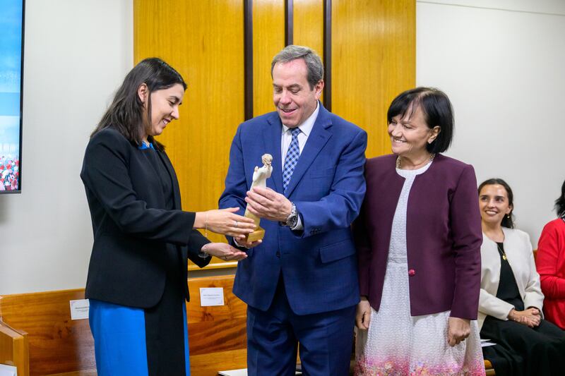 El élder Eduardo Gavarret y la hermana Norma Gavarret entregan un reconocimiento a Judith Marín durante la ceremonia "Mujeres que iluminan" en Santiago, Chile, en marzo de 2026.