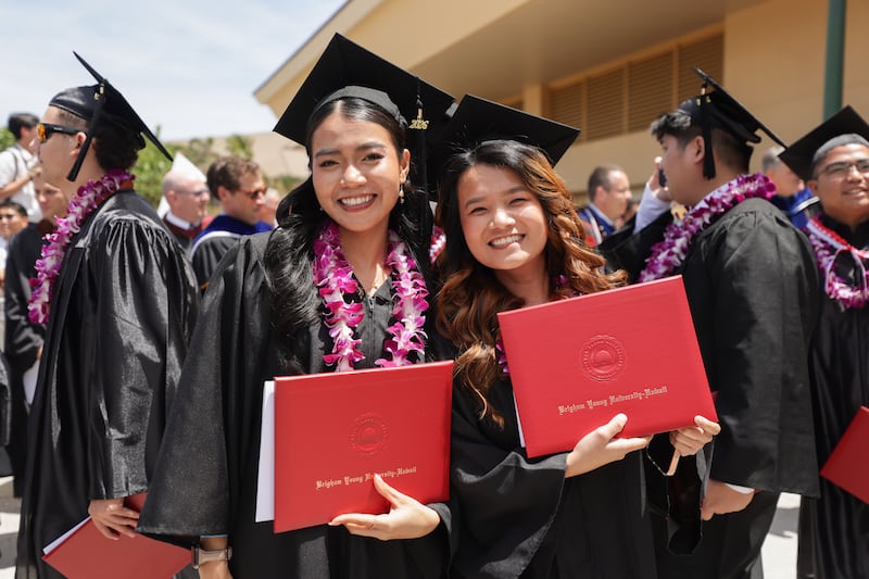 Los graduados de BYU–Hawaii se toman fotos frente al Cannon Activities Center después de la ceremonia de graduación el viernes 17 de abril de 2026, en Laie, Hawái.