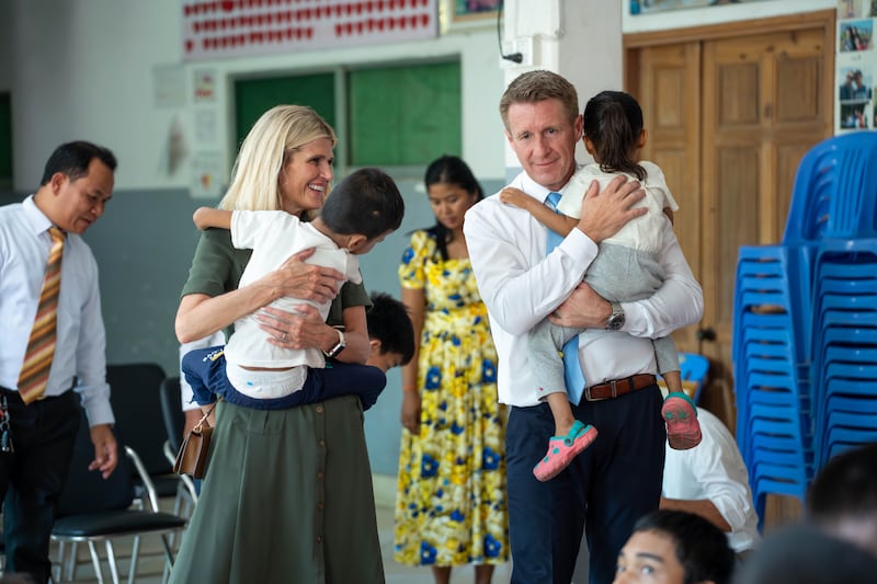 El Presidente General de los Hombres Jóvenes, Timothy L. Farnes, a la derecha, y su esposa, la hermana Linsey Farnes, sostienen a niños pequeños durante su visita al Centro Nacional para Bebés y Niños en Camboya el 23 de mayo de 2026.
