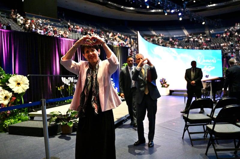 La hermana Susan Bednar, izquierda, y el élder David A. Bednar, derecha, hacen un signo de corazón a los asistentes a la Conferencia de Mujeres de BYU, en el Marriott Center en Provo, Utah, el viernes 1 de mayo de 2026.