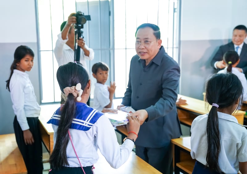 El Ministro Borin entrega libros y lápices a estudiantes en las aulas renovadas donadas por la Iglesia en el distrito de Dambae, Camboya, el 7 de junio de 2025.