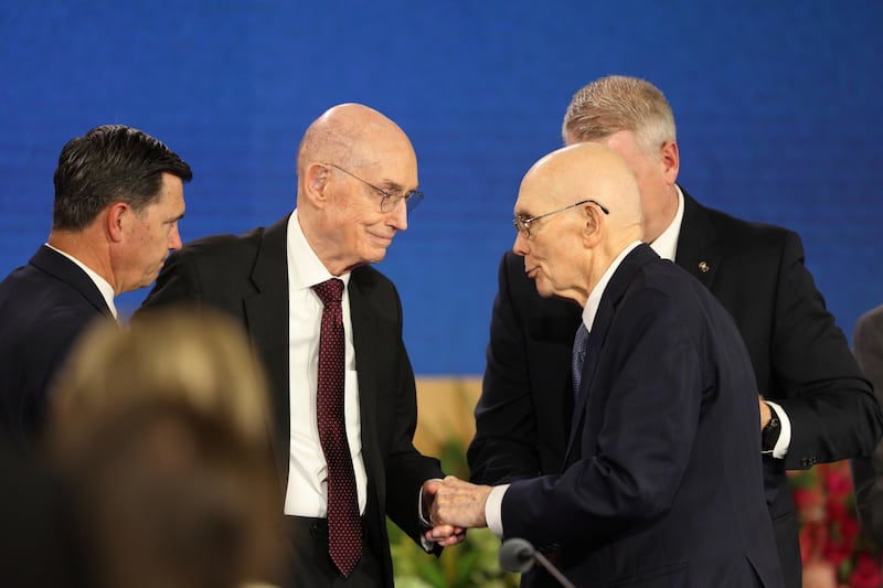 El presidente de la Iglesia, Dallin H. Oaks, centro derecha, estrecha la mano del presidente Henry B. Eyring, primer consejero de la Primera Presidencia.